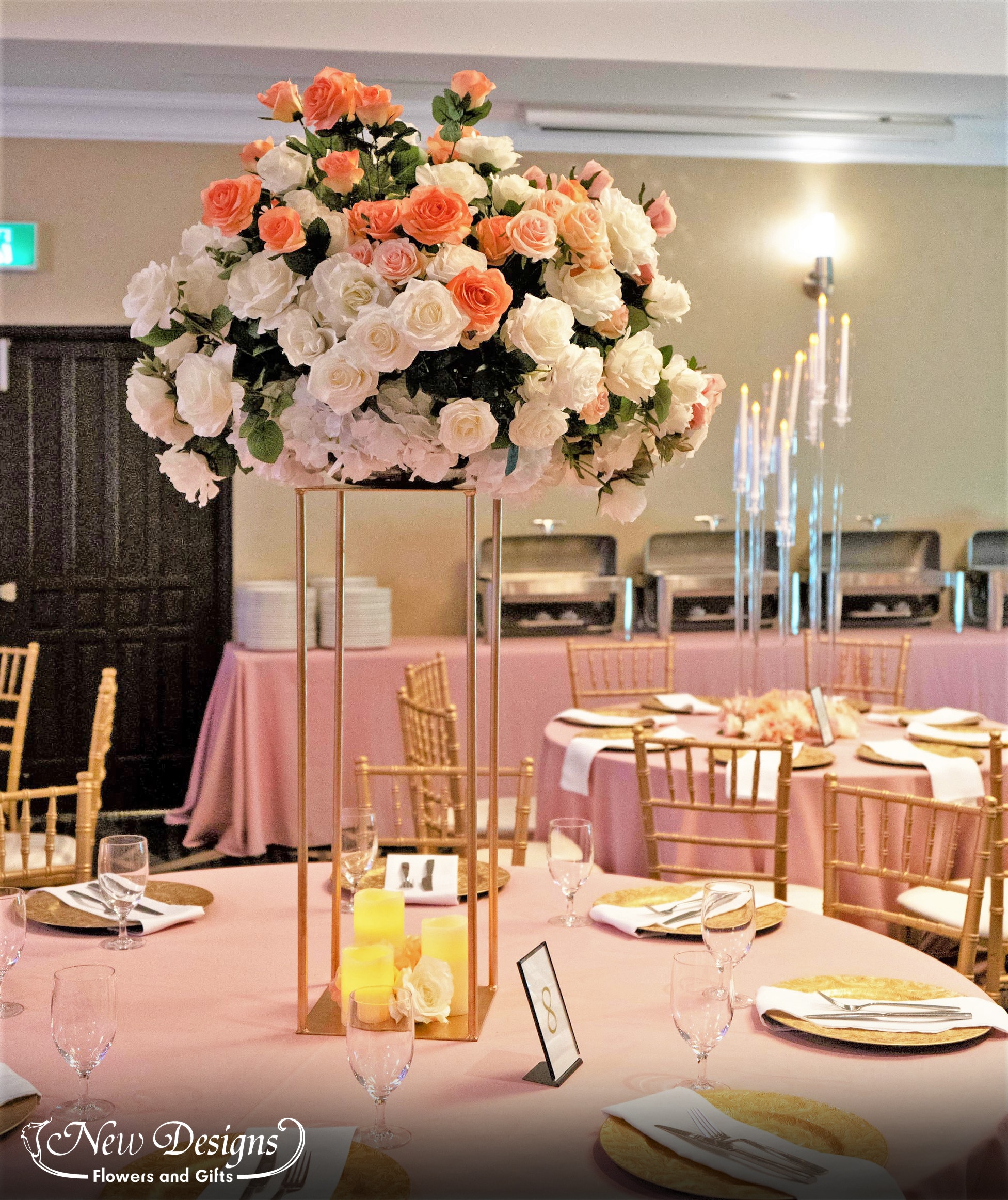 A tall centerpiece on a 4 posted metal frame, topped with a compact arrangement of roses in whites nudes and oranges.